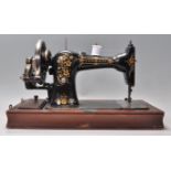 An early 20th Century singer style wooden cased sewing machine with gilt floral decoration