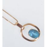 A 9ct yellow gold pendant necklace of rounded form set with an oval faceted cut blue stone. On a 9ct