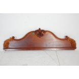 A 20th Century carved mahogany bed headboard of serpentine form having a carved scrolled leaf