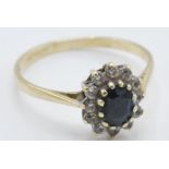 An English hallmarked 9ct yellow gold ladies dress ring having a central dark blue stone with a halo