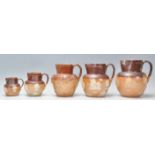 A group of five graduating 19th Century Doulton Lambeth stoneware jugs having applied raised white