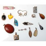 A collection of fifteen silver pendants to include an abalone shell pendant, an oval red stone