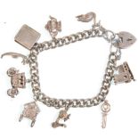 A vintage silver charm bracelet adorned with many charms and having a heart clasp. Charms include