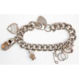 A thick link silver chain charm bracelet adorned with charms to include three textured rings, crown,