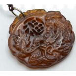 A Chinese yellow stone pendant carved into relief