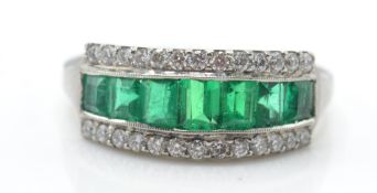 A platinum emerald and diamond ring. The ring set