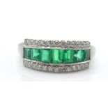 A platinum emerald and diamond ring. The ring set