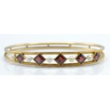 A gold pearl and garnet set bangle. The bangle set