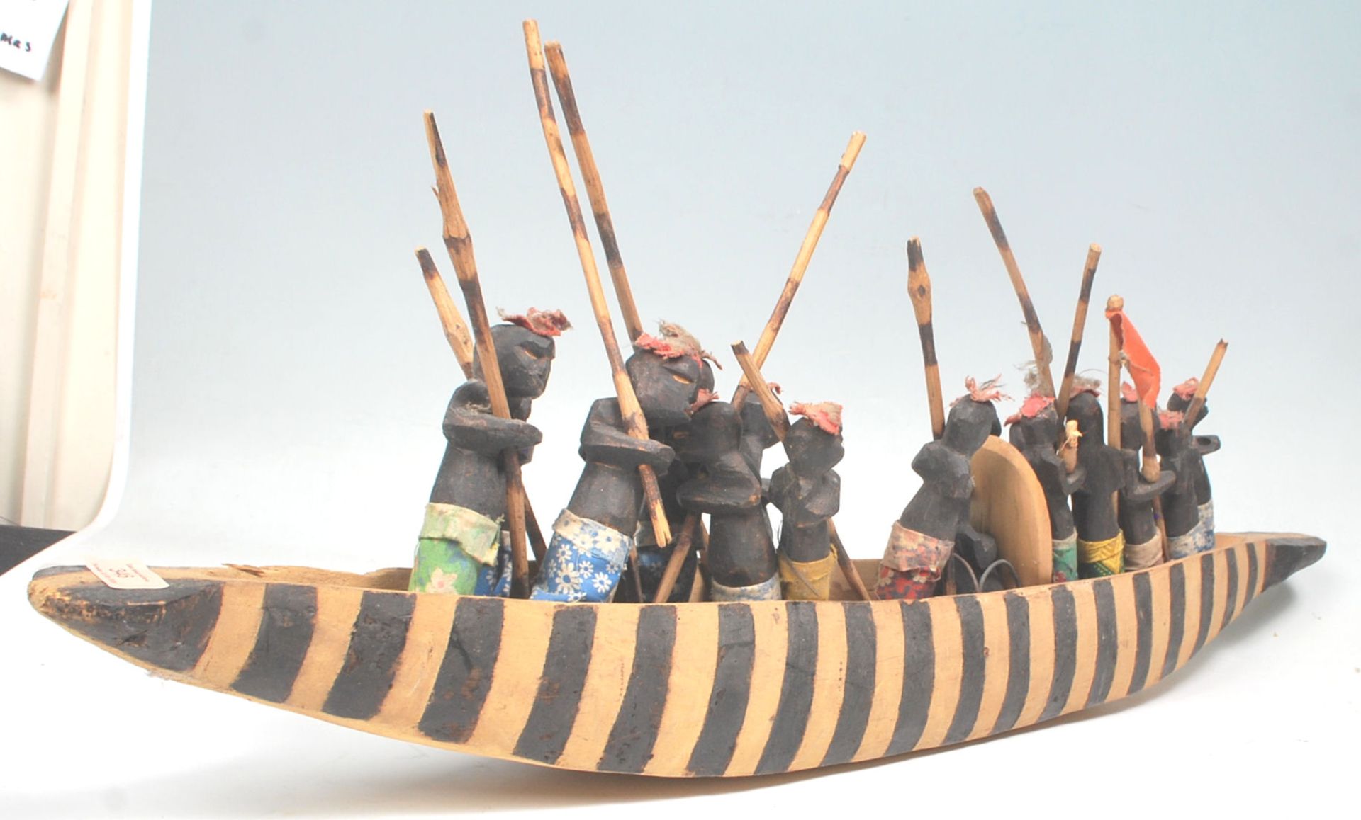 An African tribal carved wooden boat figurine complete with striped painted sides, complete with