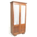 A 20th Century Edwardian French light oak bookcase cabinet with a flared top above glazed double
