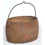 A late 19th Century Victorian iron cooking pot / cauldron having a large swing handle with hook