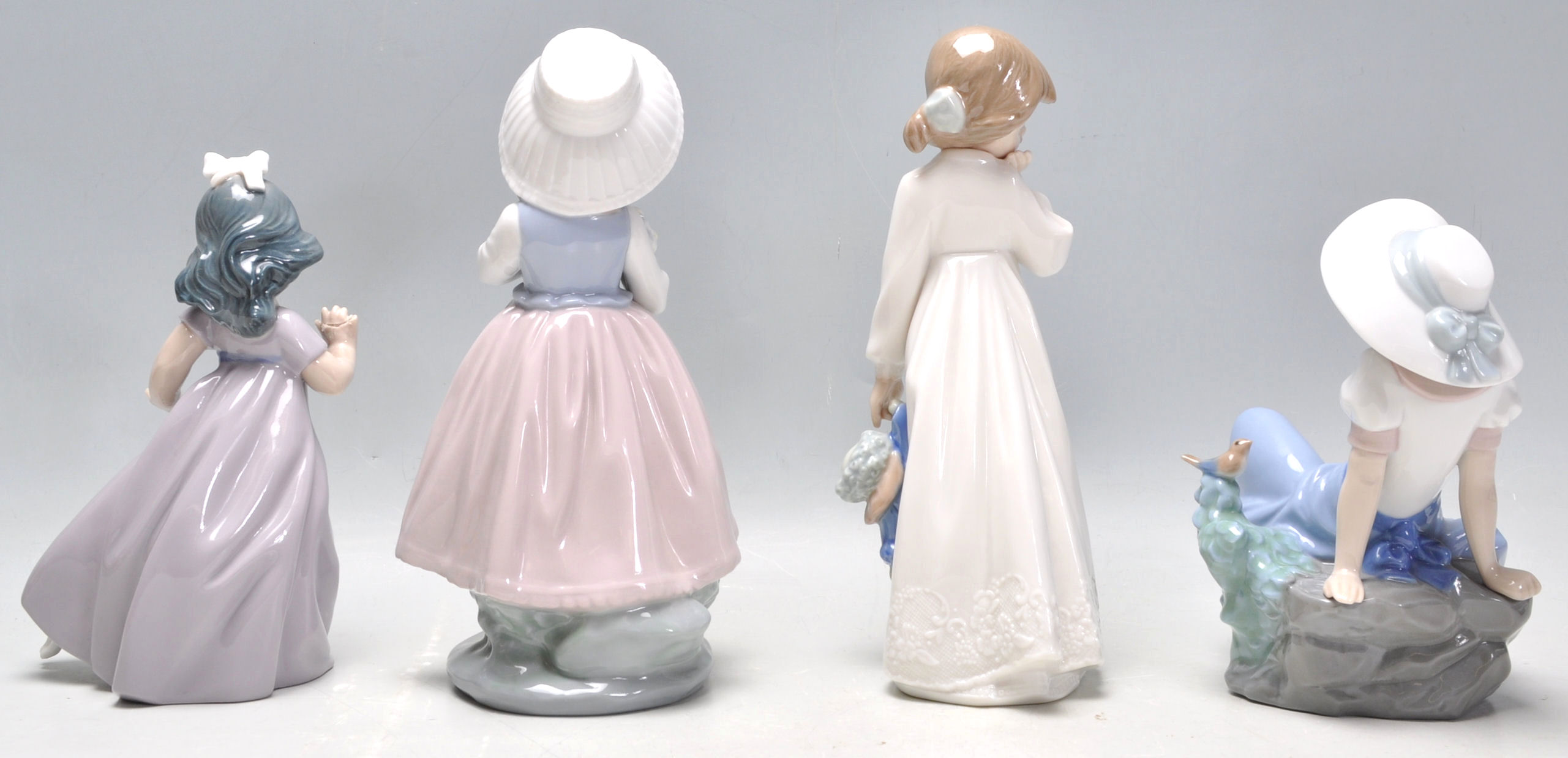 A group of four Nao porcelain figurines to include a seated girl with a perched bird, a girl in a - Image 3 of 9