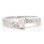 A stamped 9ct white gold ring set with a marquise cut diamond flanked by diamond accent stone