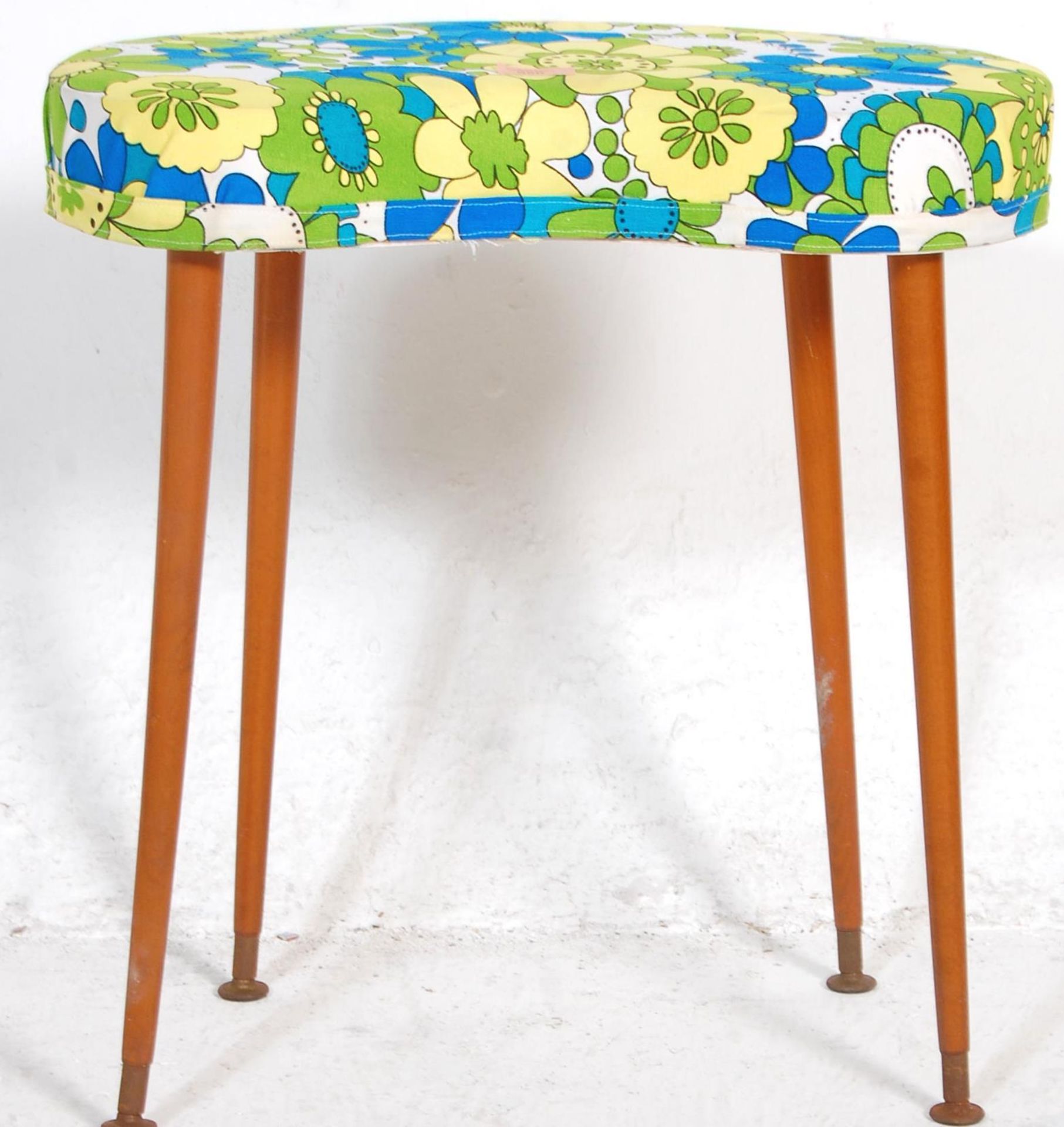 A retro vintage kidney shaped stool upholstered in blue yellow and white fabric raised on tapering