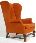 A good 17th century revival wingback armchair upholstered in an orange fabric and raised on carved