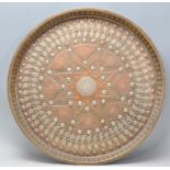 A 20th Century Middle Eastern brass and copper wall charger of circular form having inlaid white