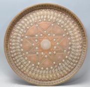 A 20th Century Middle Eastern brass and copper wall charger of circular form having inlaid white