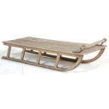 A vintage 20th Century scrubbed wooden sledge / sled / sleigh having a turned handle to the top