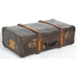 A vintage 20th Century dark brown leather and wood bound suitcase travel trunk. The lid open opens