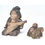 An Antique Japanese clay figure in the form of a seated gashsia playing a musical instrument with