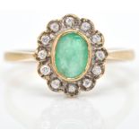 A hallmarked 9ct emerald and white stone cluster ring. The ring set with an oval mix cut emerald