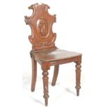 A 19th Century Victorian Oak hall chair with an armorial carved shaped back set upon panel seat rest