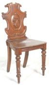 A 19th Century Victorian Oak hall chair with an armorial carved shaped back set upon panel seat rest