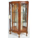 A 20th Century Queen Anne walnut china display cabinet having a bowed serpentine front with three
