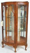 A 20th Century Queen Anne walnut china display cabinet having a bowed serpentine front with three