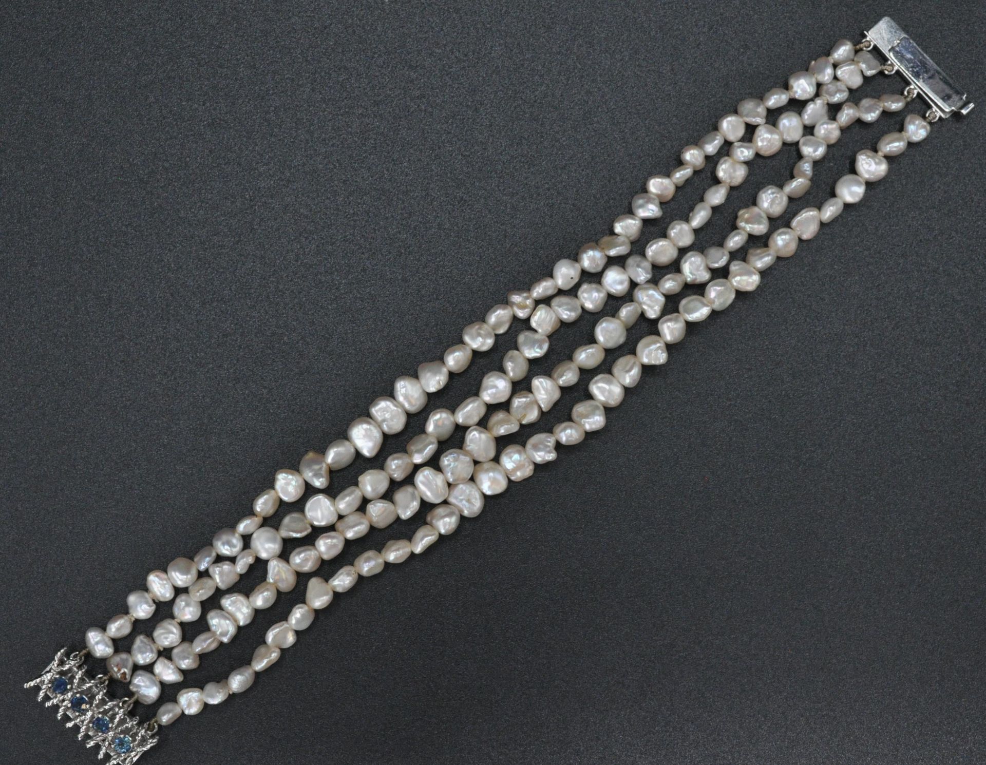 A 14ct white gold 585 4 strand baroque pearl bracelet by JKA . The bracelet united by a 14ct gold