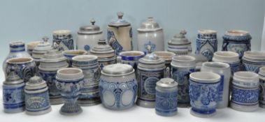 A large collection of German blue and grey stoneware jugs and beer steins, some having pewter