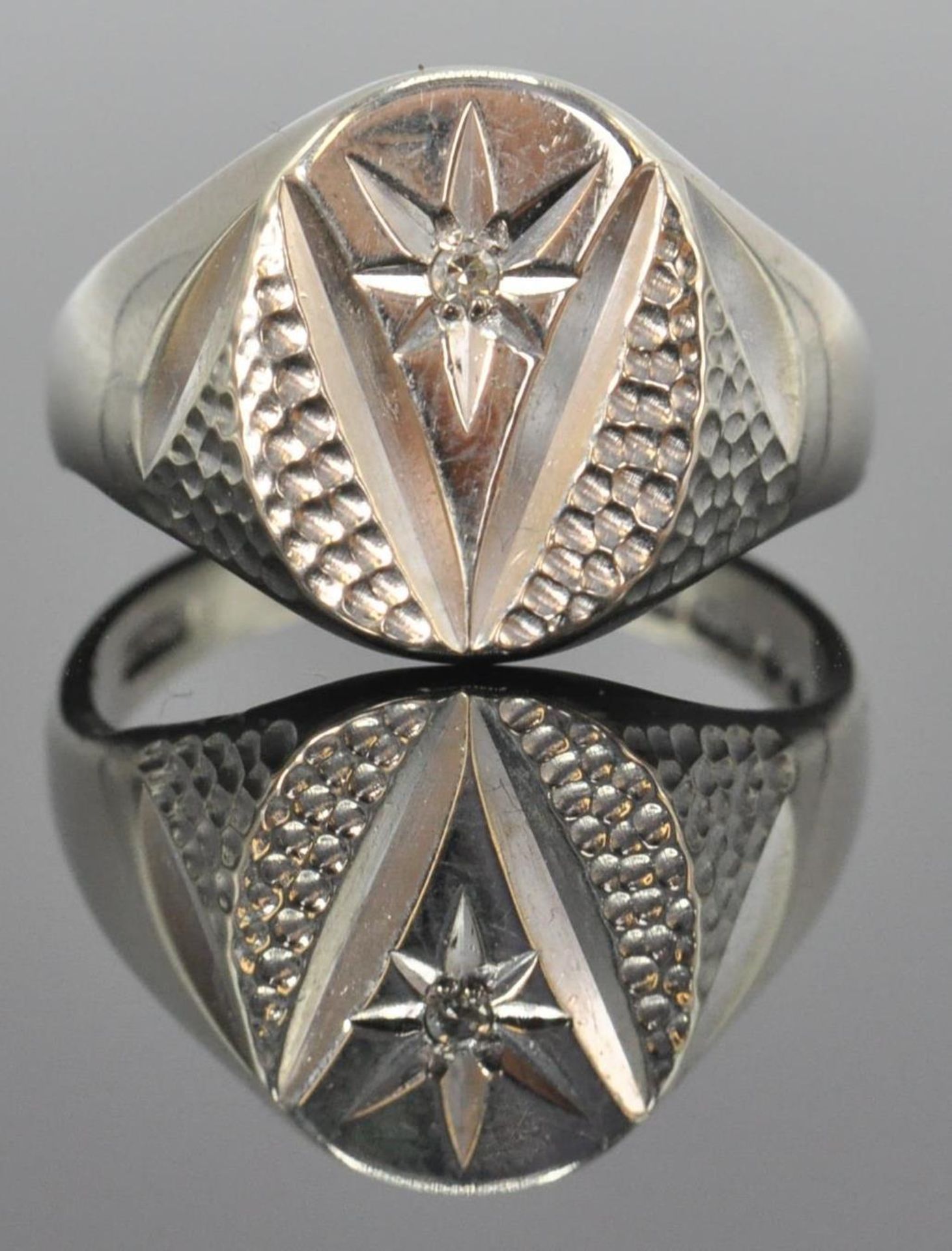 A 9ct white gold hallmarked signet ring. The ring with sunburst cartouche inset with round cut