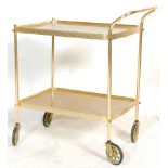 A retro 20th Century brass two tier tea trolley having formica teak wood effect tops. Raised on