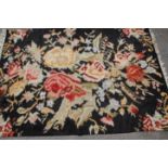 An early 20th Century Chinese floor rug having black ground with floral sprays with white tassel