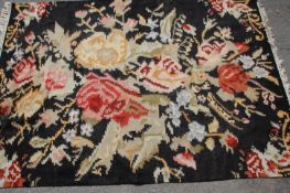 An early 20th Century Chinese floor rug having black ground with floral sprays with white tassel