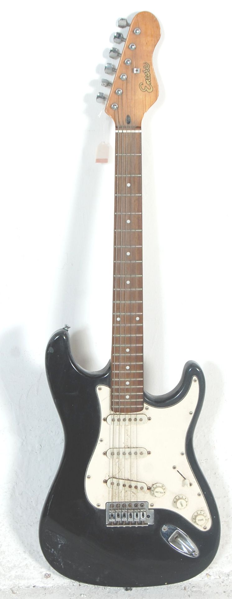 A Fender Stratocaster style Encore six string electric guitar having three control knobs with a