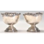 A near pair of early 20th Century silver footed bowls each having raised scrolled design raised