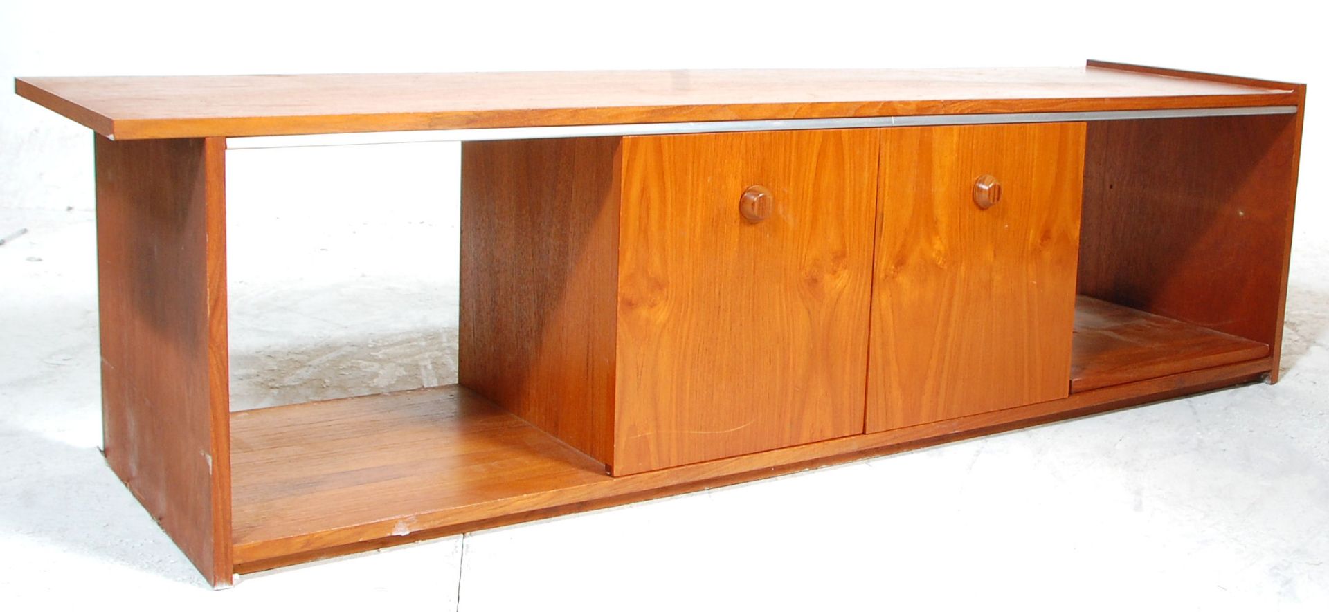 A low mid 20th Century retro teak wood unit / sideboard having sliding doors across open sections