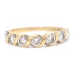 A stamped 750 18ct gold ladies ring having a twist design set with seven round cut white stones.