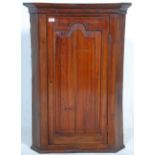 A 19th century fruitwood George III corner cabinet. Full length fielded panel door with enclosed