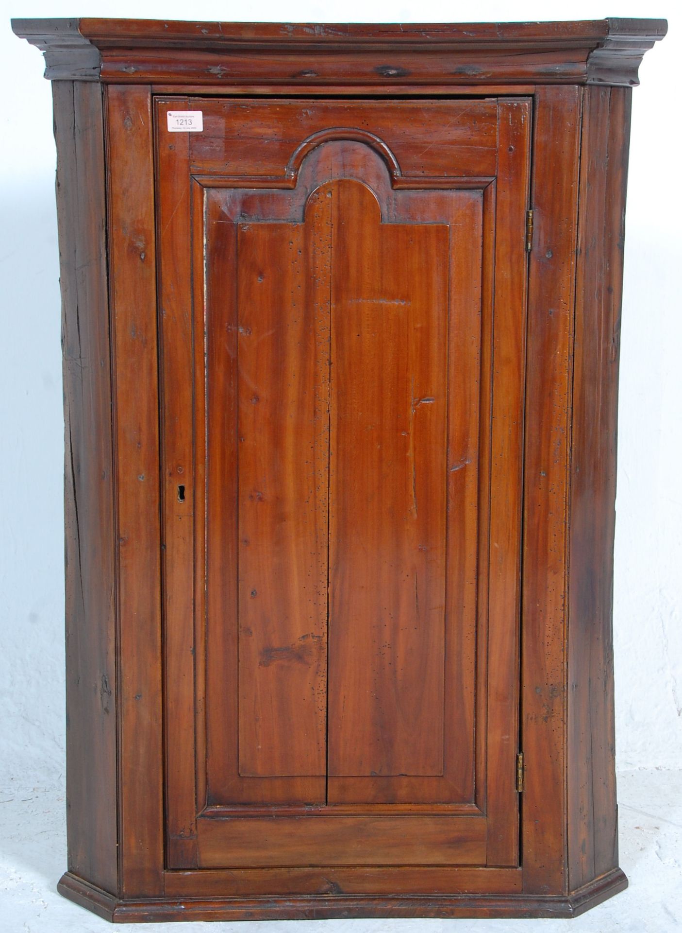 A 19th century fruitwood George III corner cabinet. Full length fielded panel door with enclosed