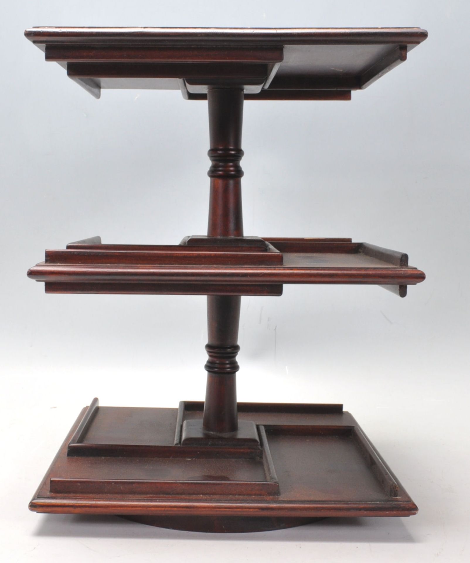 An antique style mahogany desktop revolving bookcase of small proportions with segregated shelves on