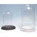 Two vintage glass display domes dating from the early 20th Century with both raised on circular