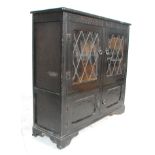 A Jacobean revival ebonised oak double door astragal glazed bookcase with butterfly hinges set