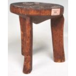 An Australian aboriginal wooden tribal stool having a around seat with three carved legs below,