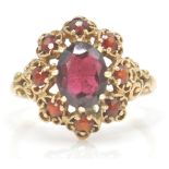 A 9ct gold hallmarked cluster ring. The ring set with oval facet cut garnet within a pierced setting