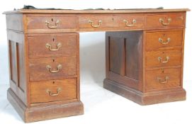 An early 20th Century oak pedestal office / library desk having a green leather top with three