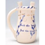 An early 20th century mottoware puzzle jug in blue and white colourway having notation ' Drink the
