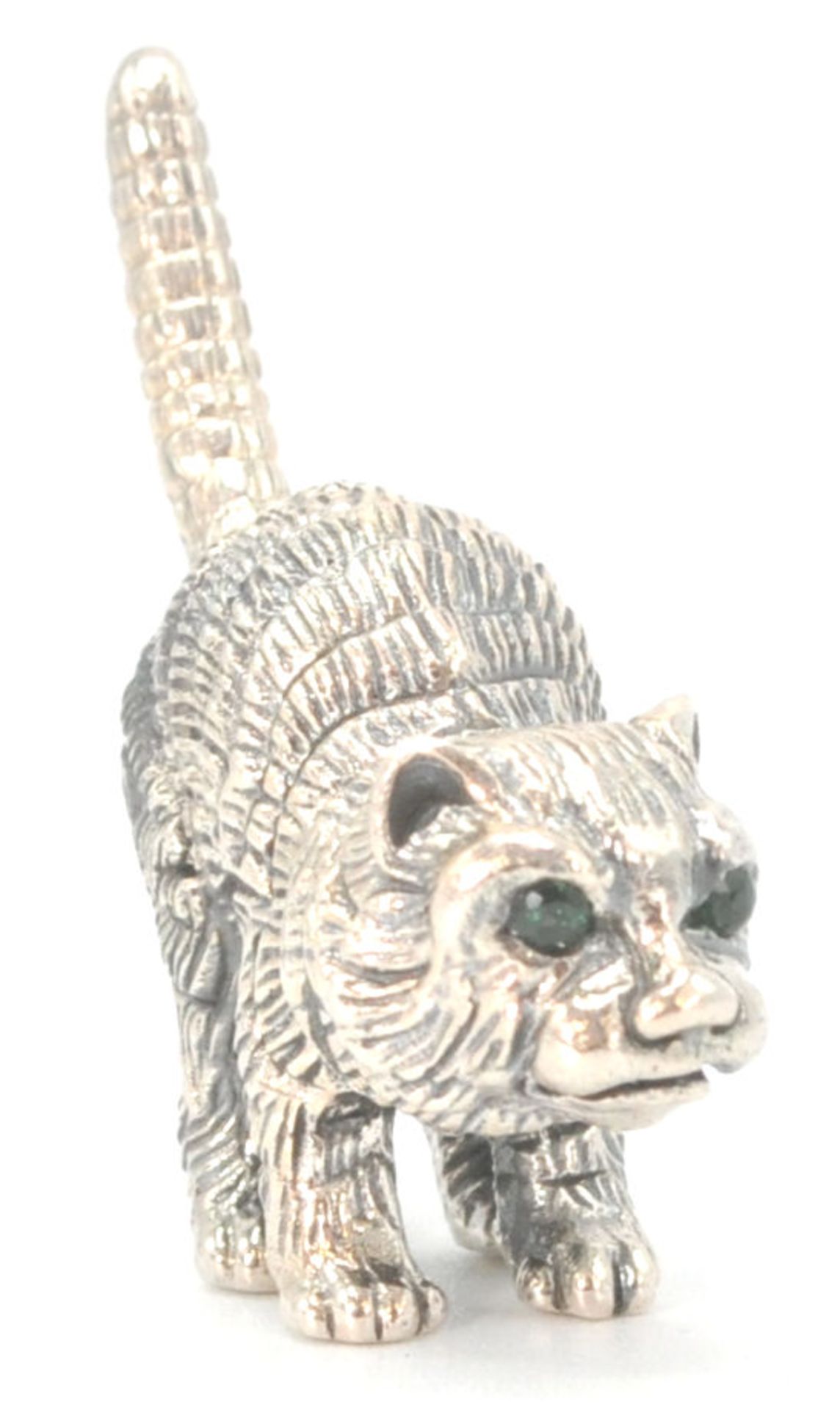 A stamped sterling silver ornament in the form of a pouncing cat set with emerald coloured eyes.