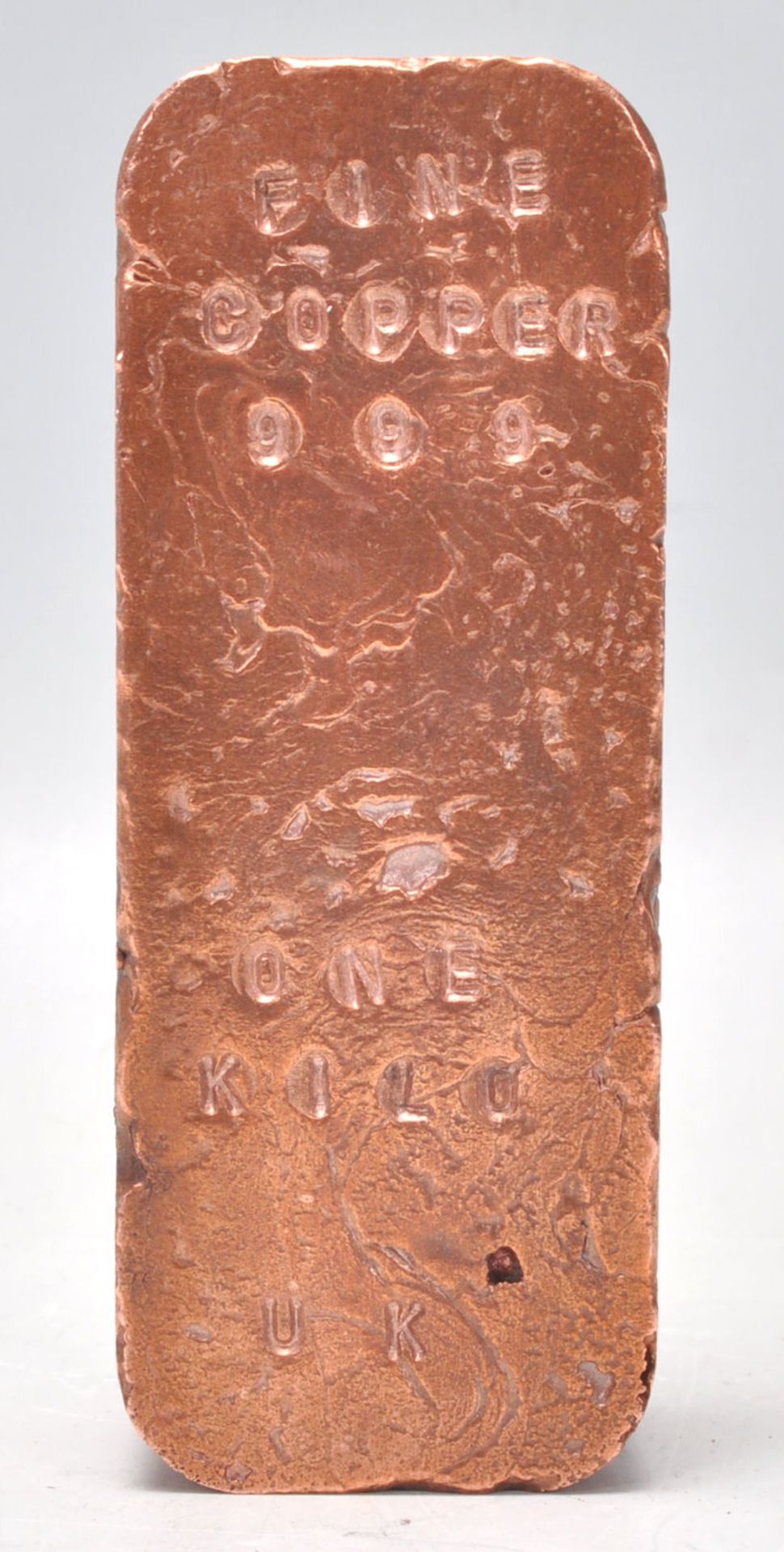 A copper bullion bar inscribed with " FINE COPPER .999 ONE KILO UK ".